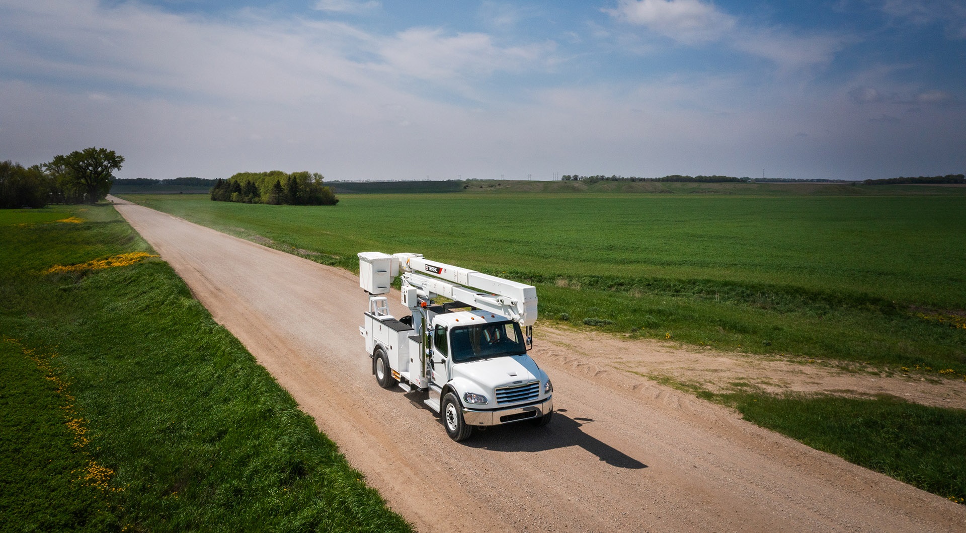 Terex bucket truck driving down a gravel road
