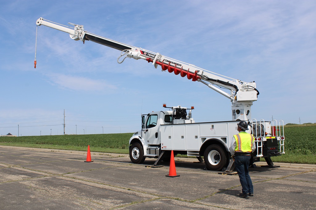Utility worker operating digger derrick
