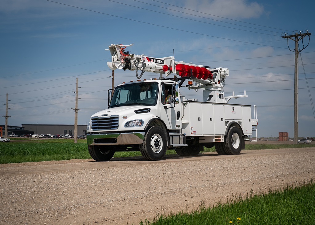 Terex digger derrick driving on a gravel road.