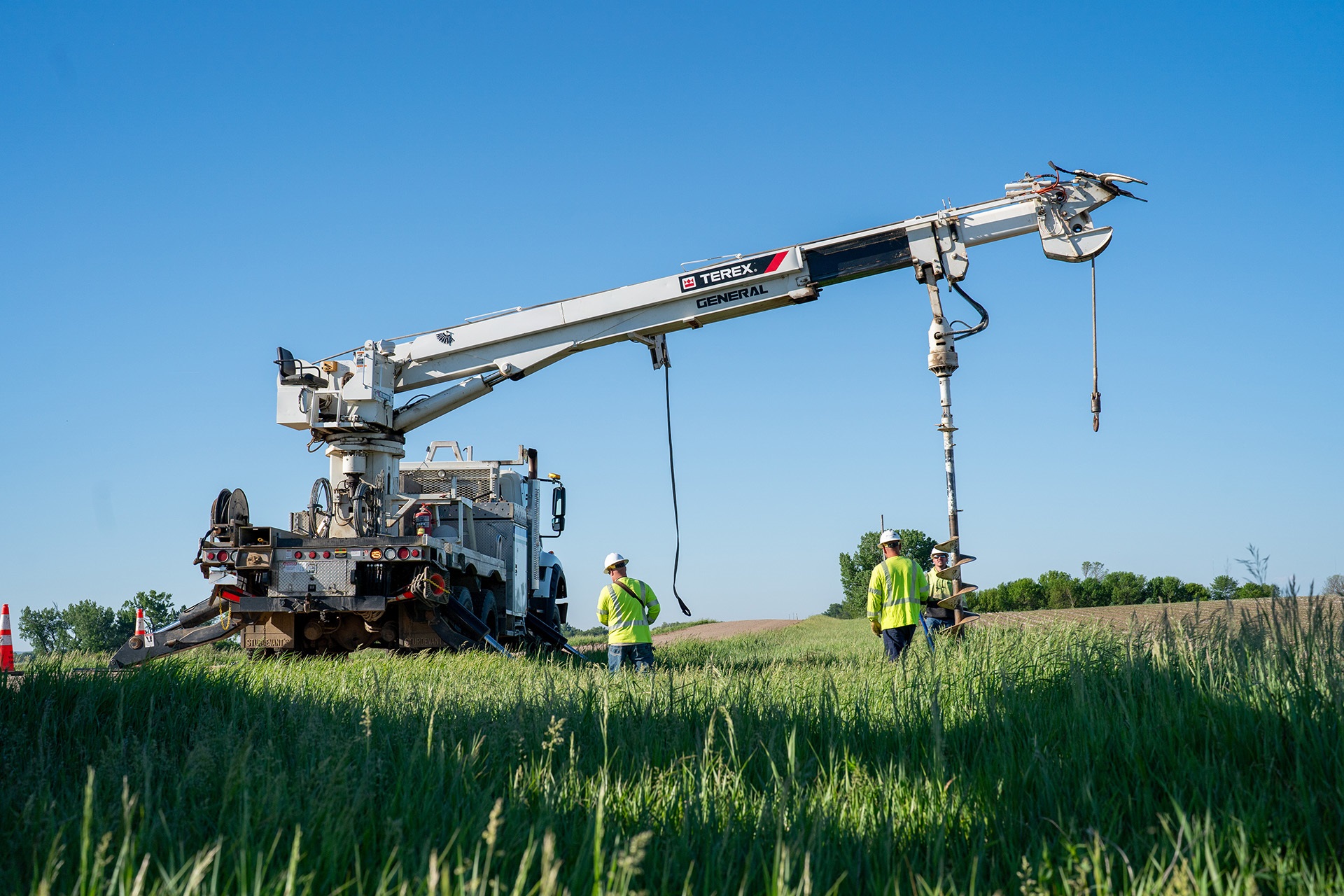 Lineworkers digging hole with Terex digger derrick